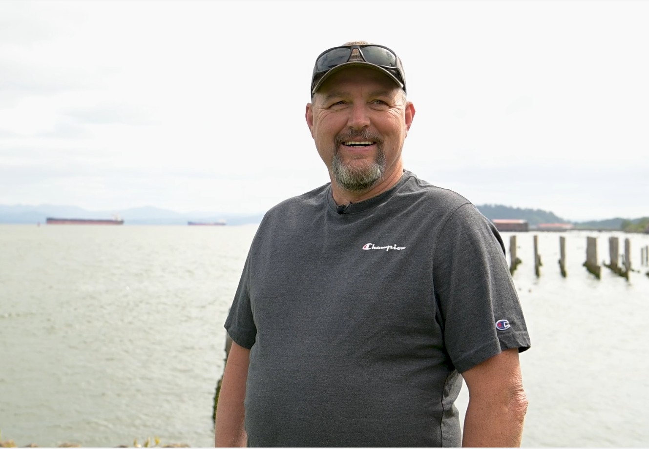 A smiling fisherman stands on the river front of Astoria, Oregon
