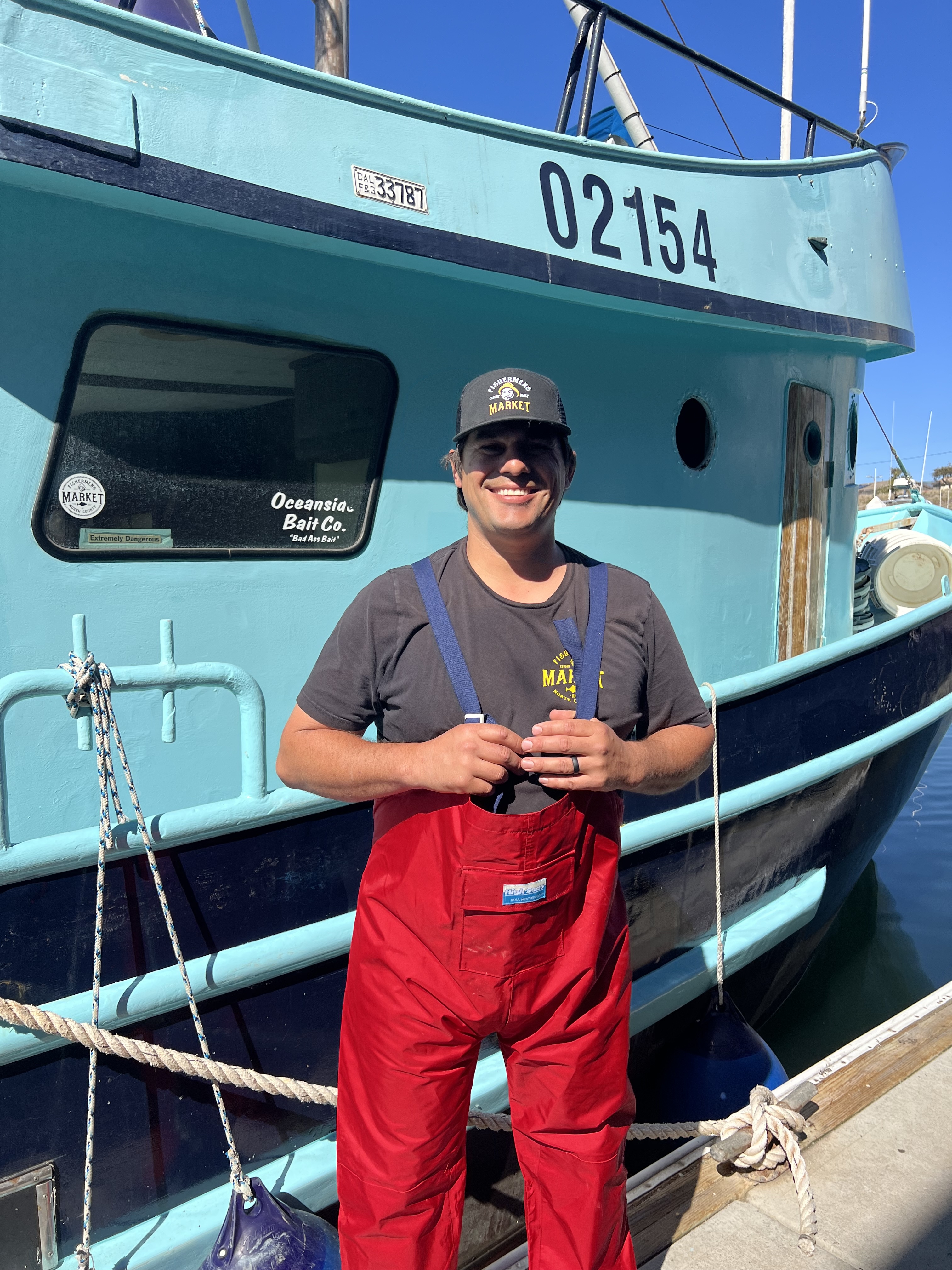 Travis in front of his fishing vessel