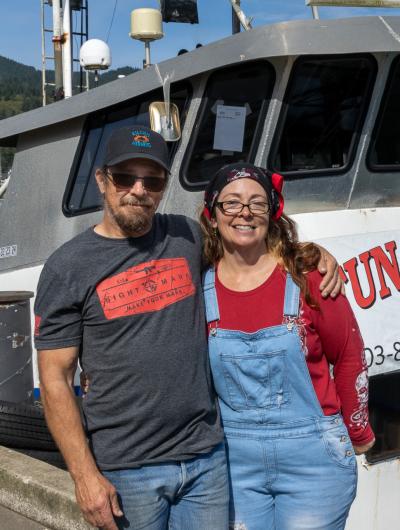 Man and woman standing in front of a fishing vessel