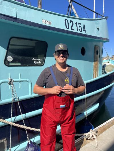 Travis in front of his fishing vessel