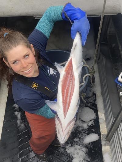 Amy Sharp poses onboard a boat showing off a large salmon filleted down the middle.