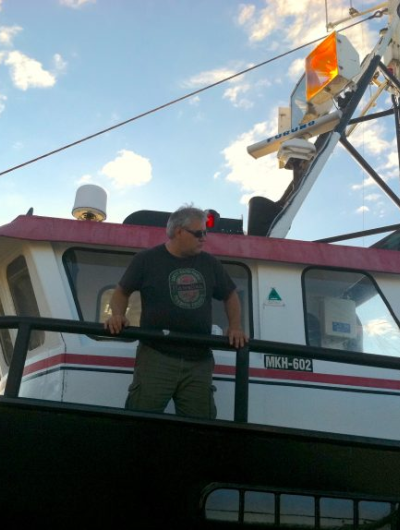 Dave Sones stands on the deck of his ship looking out over a railing.